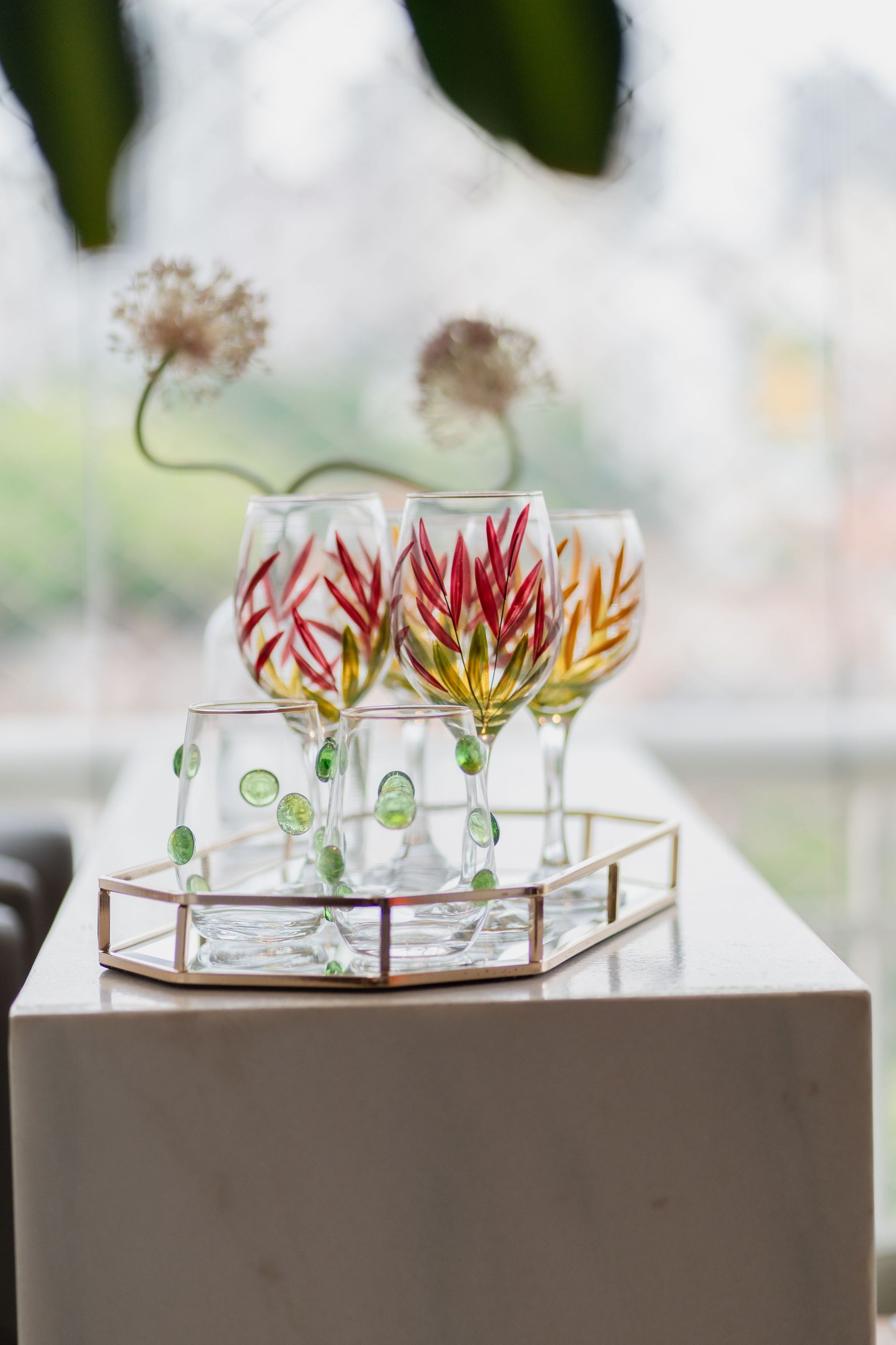 Stunning hand-painted wine glasses with floral designs elegantly arranged on a marble surface.